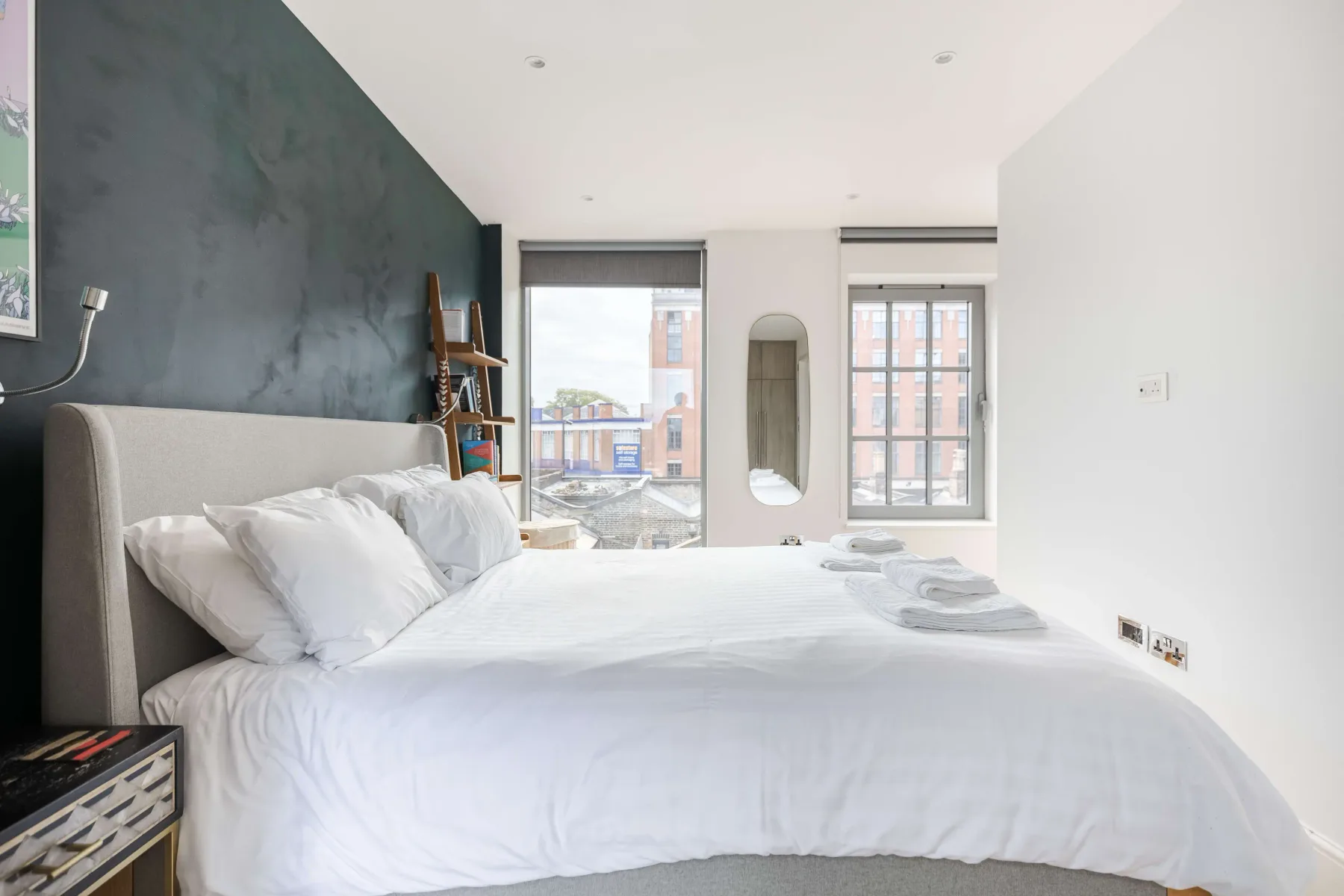 A bright bedroom with a neatly made bed and large windows.