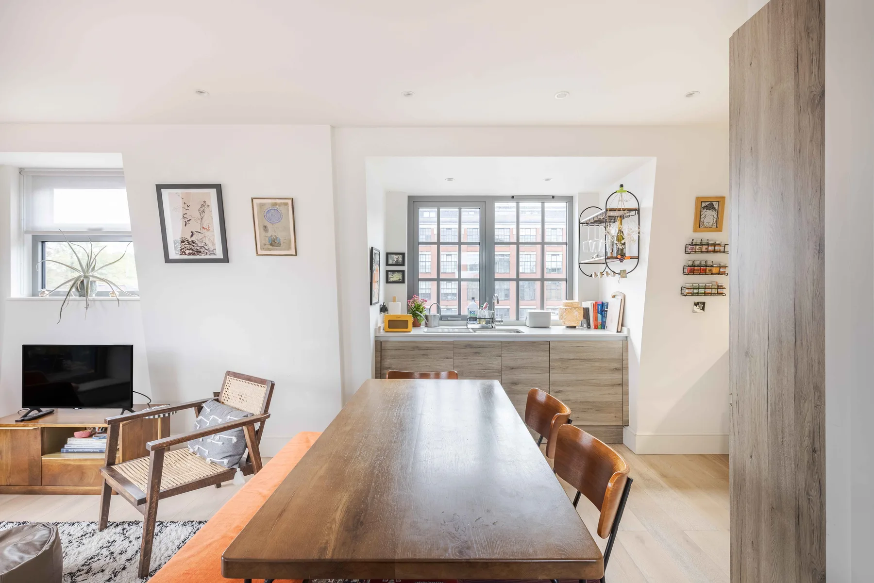 A bright dining area with a long wooden table beside a kitchen window.