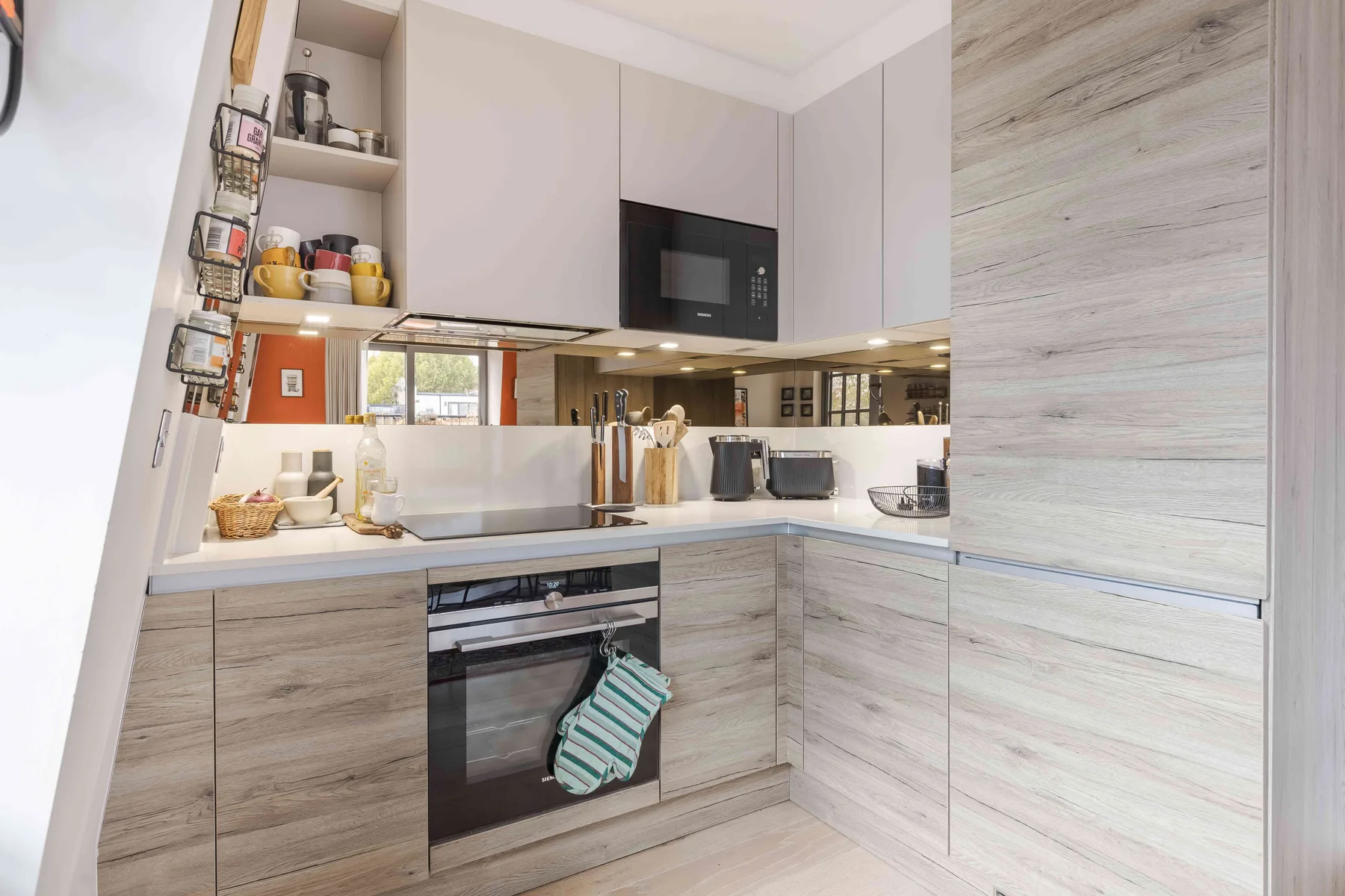 A modern kitchen with pale cabinetry, a countertop, and built-in appliances.