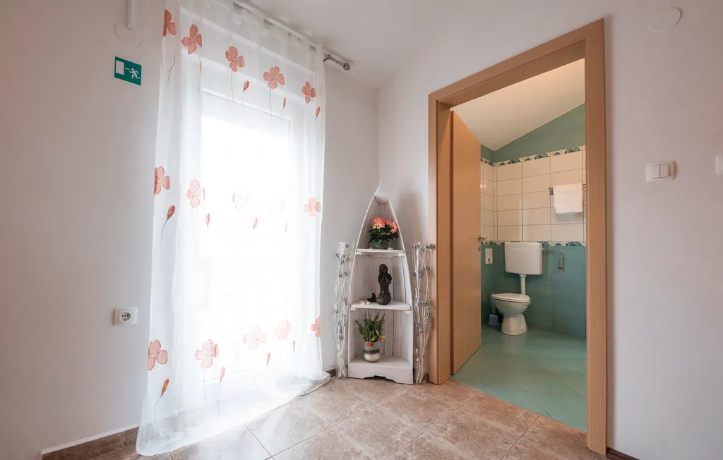 A bright room with a floral-curtained window and an open doorway to a bathroom.