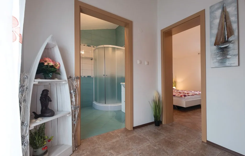 A hallway opens onto a bathroom and a bedroom, with a decorative shelf beside the doorway.