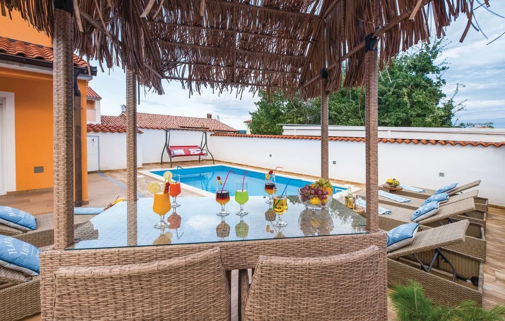 Una zona exterior cubierta con asientos da a una piscina y una mesa decorada.