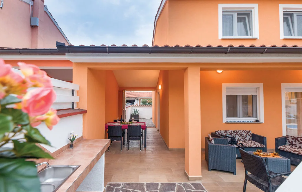 An orange courtyard patio has outdoor seating and a covered passage.