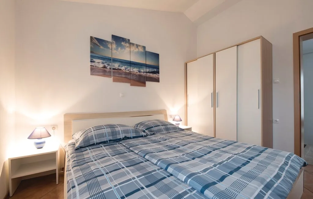 A bedroom with a bed covered in blue plaid bedding and a wardrobe.