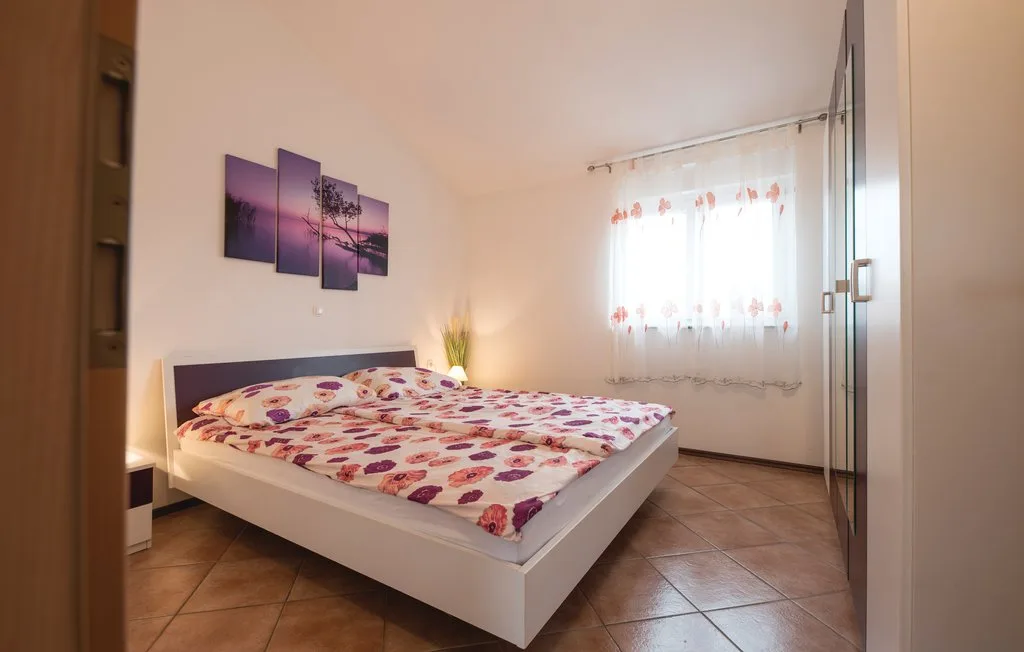 A bedroom with a bed, patterned bedding, and a bright window.