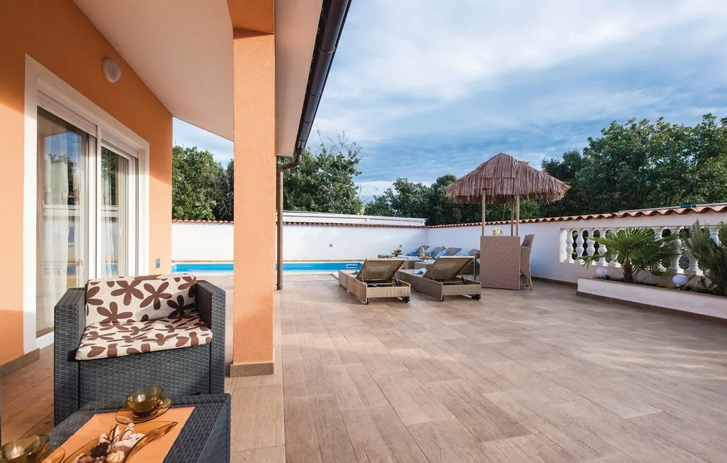 A tiled outdoor terrace with seating, a small pool, and a thatched umbrella.