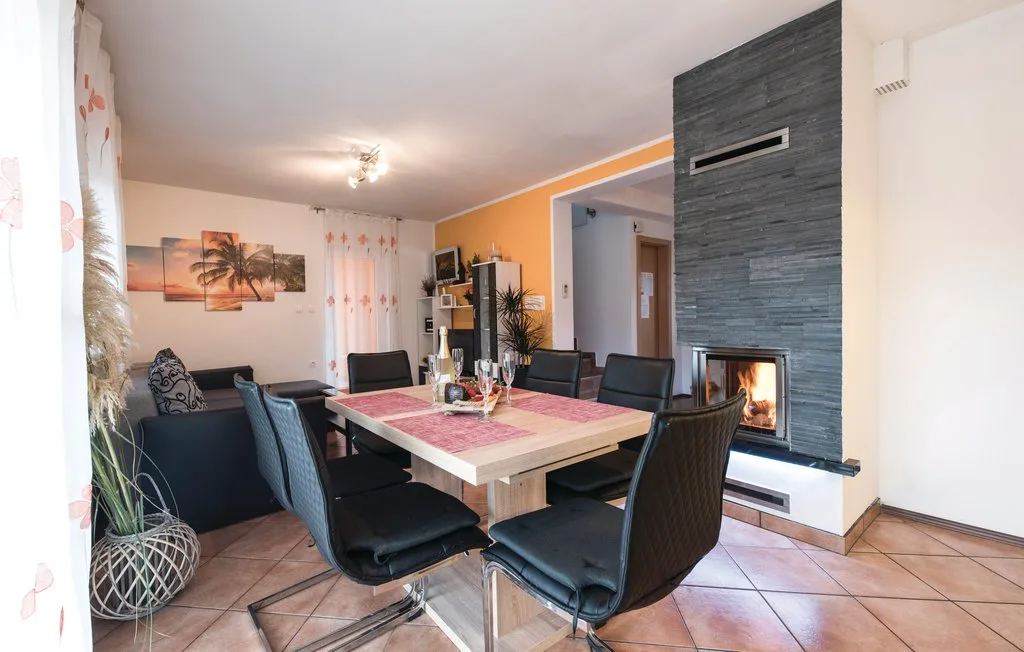 A living and dining room with a table, seating, and a fireplace.