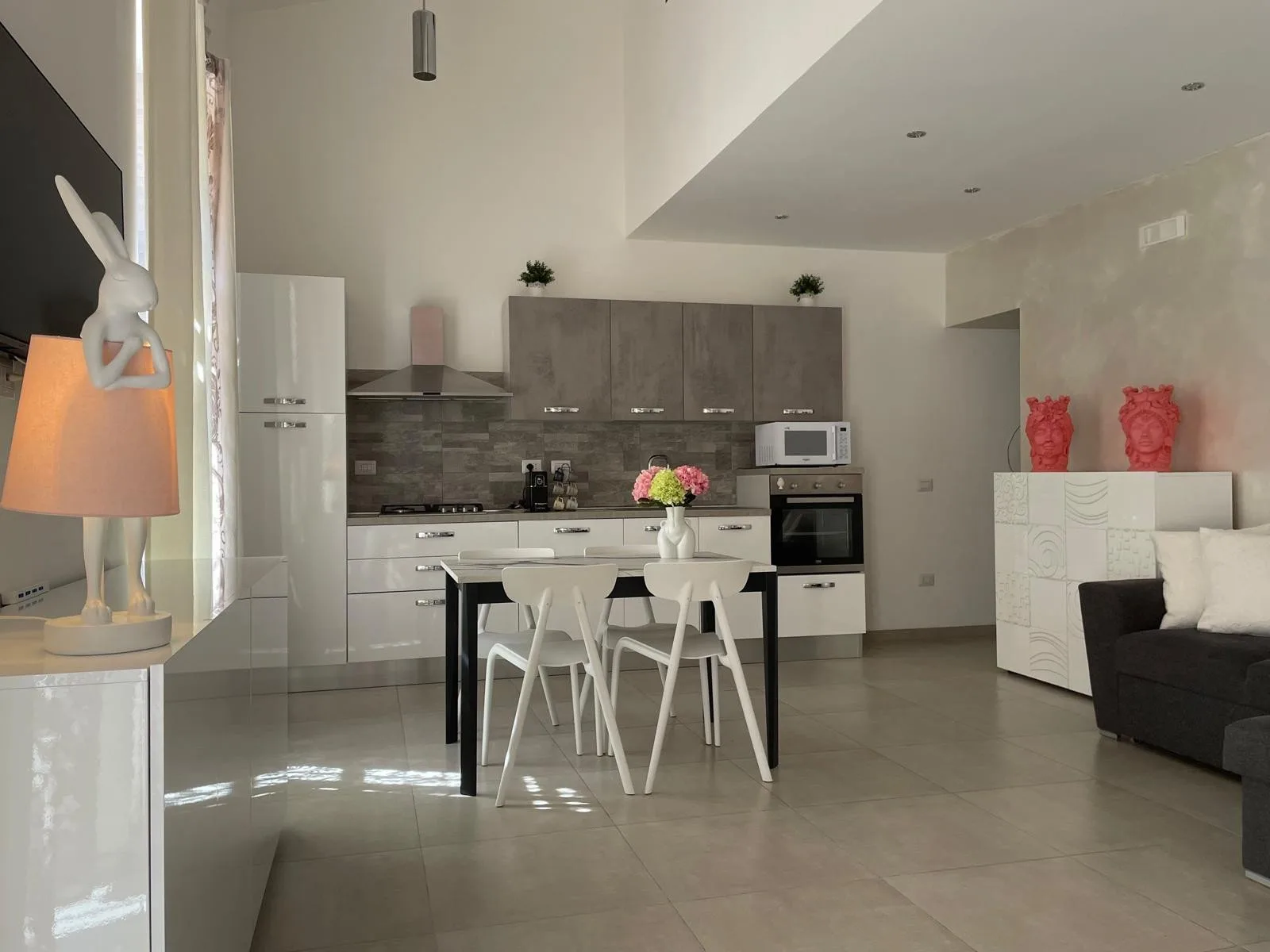 Cocina y comedor de concepto abierto con una mesa y sillas blancas.
