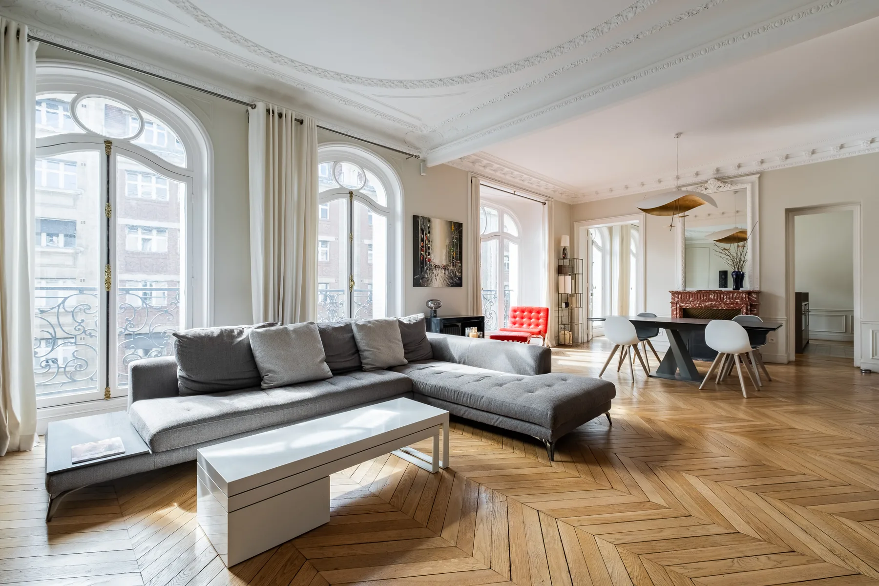 A bright living room with tall arched windows, a sectional sofa, and a dining area.