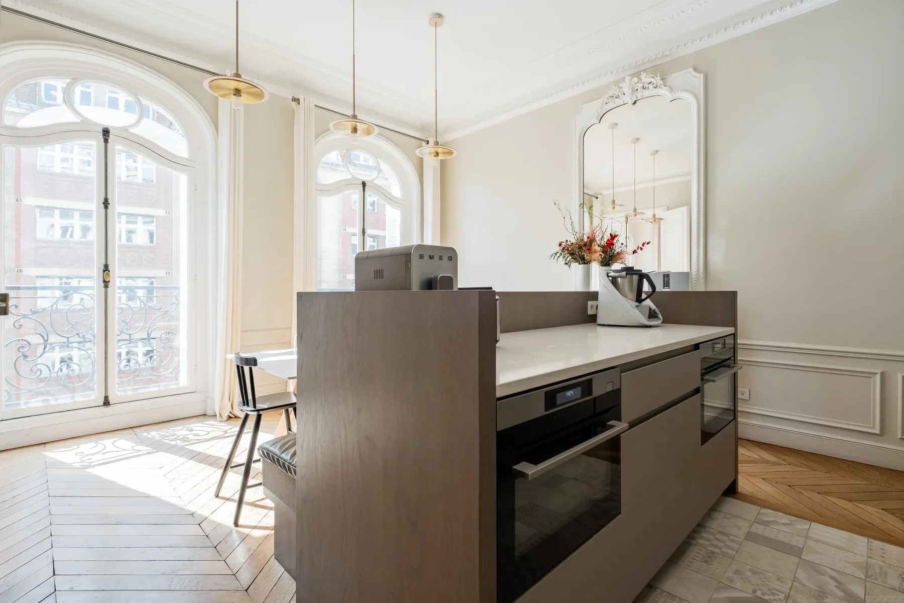 A bright kitchen with a large island and tall arched windows.