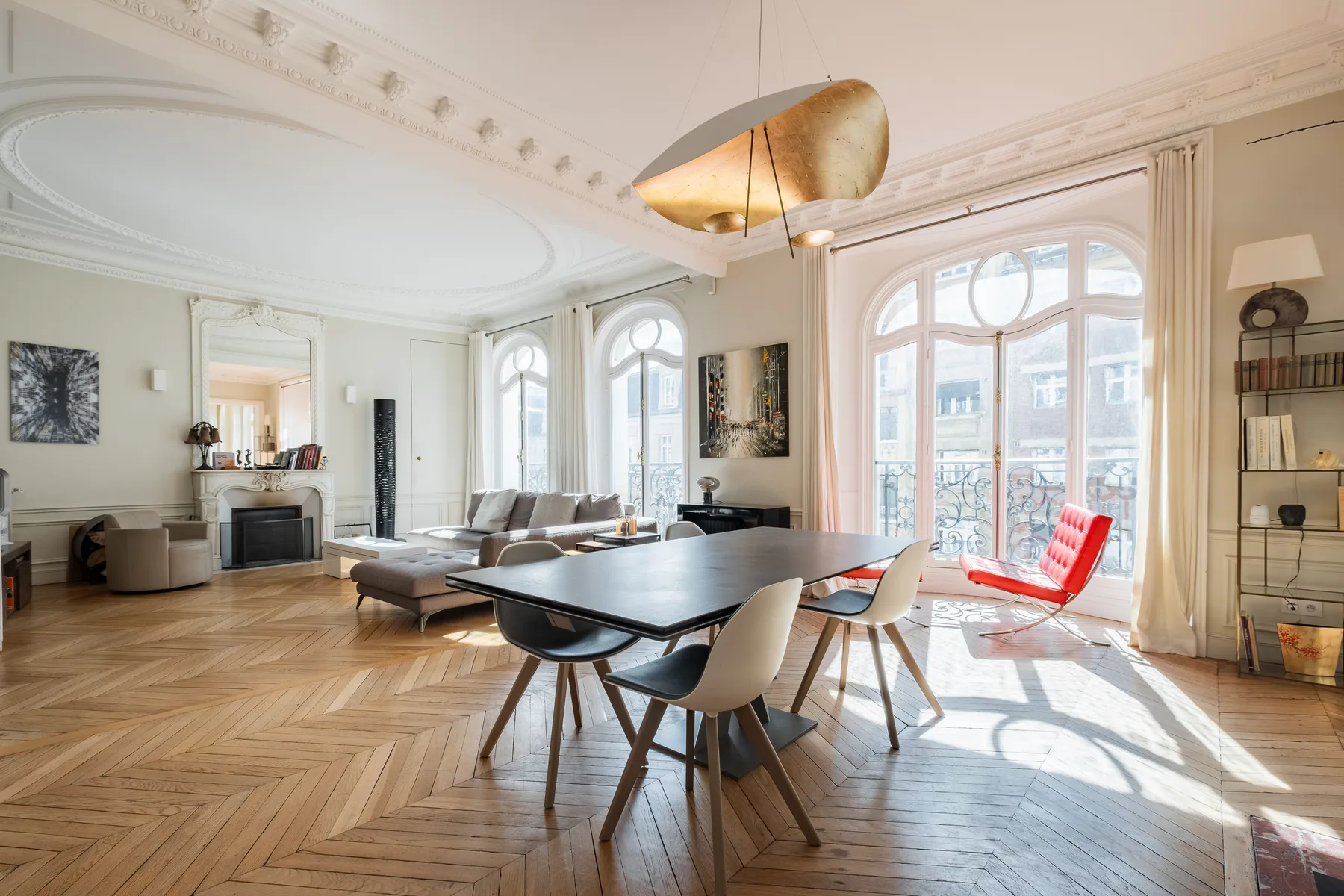 A bright living and dining room with large arched windows and contemporary seating.