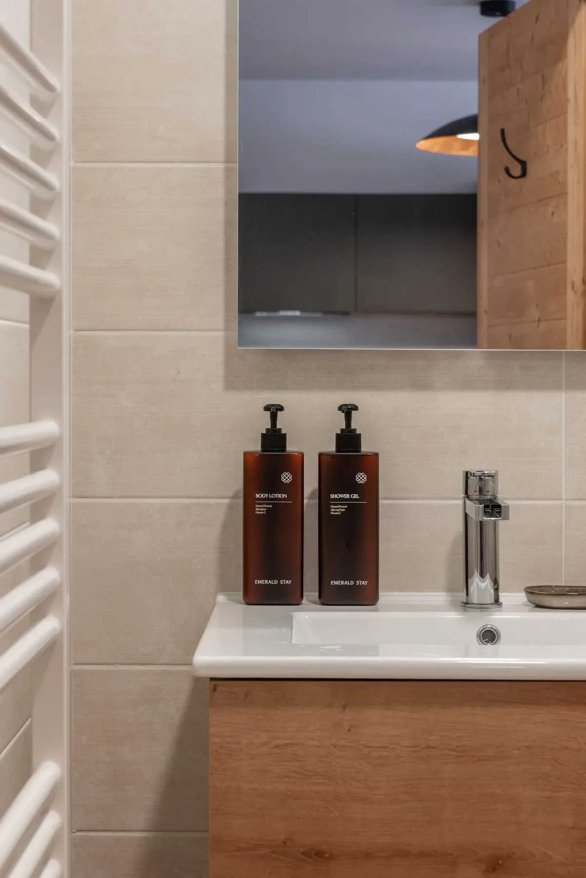 Modern bathroom with wooden vanity, large mirror, glass shower enclosure, and white heated towel rail, in a neutral-toned decor.
