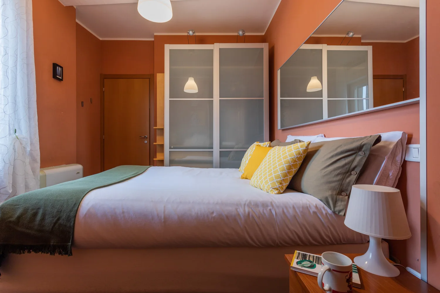 Un dormitorio con una cama, cojines de colores y armarios con puertas espejadas.