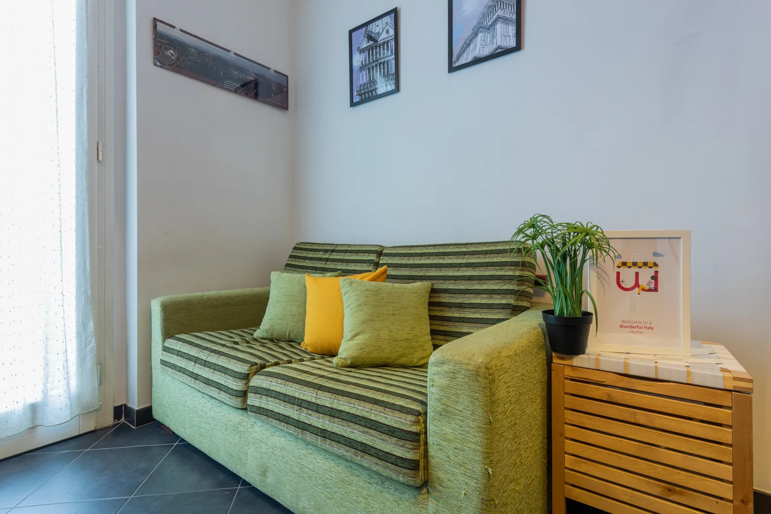 Una sala de estar con un sofá a rayas, cojines de colores y una planta en maceta.