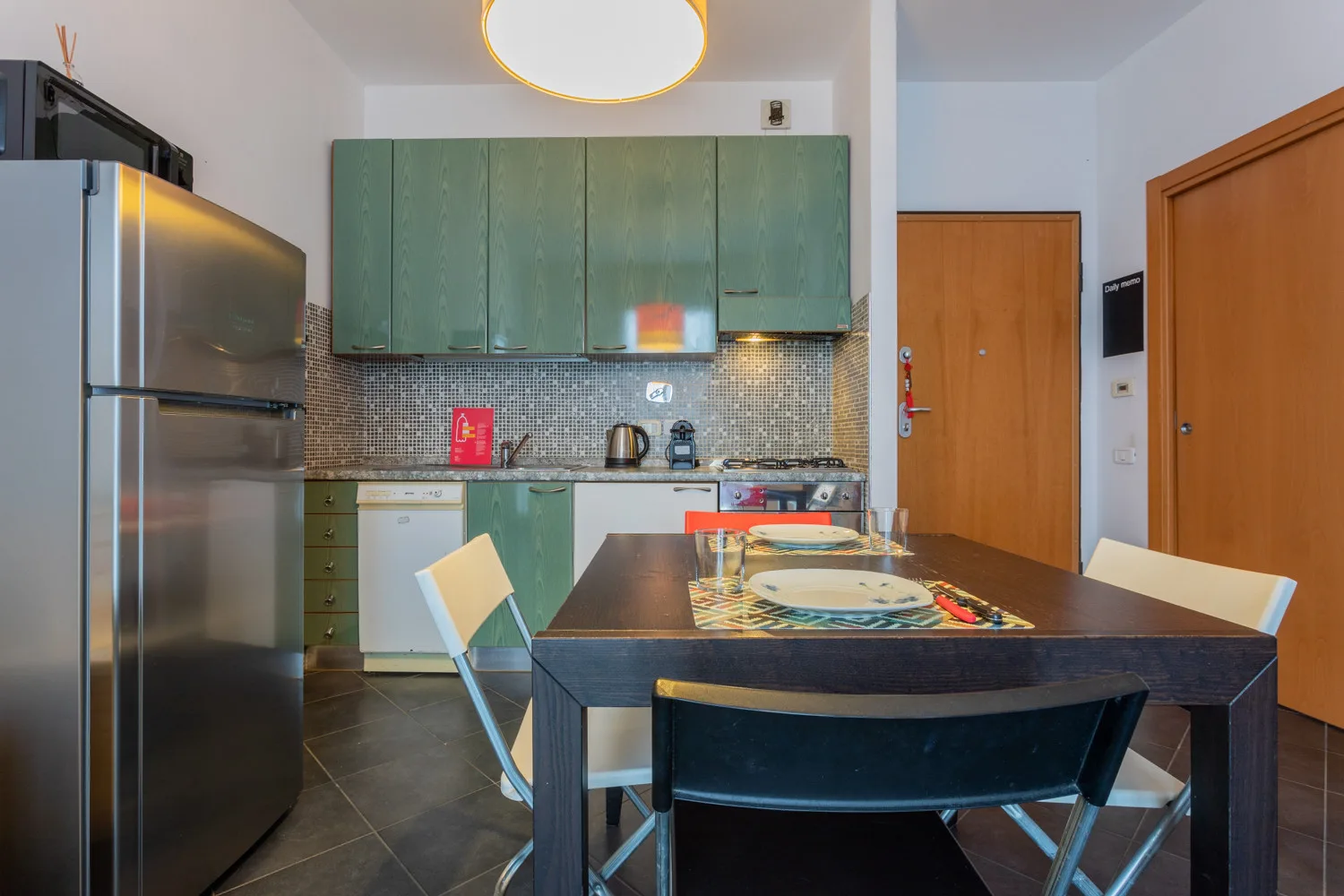Una cocina-comedor con una mesa oscura y armarios verdes.