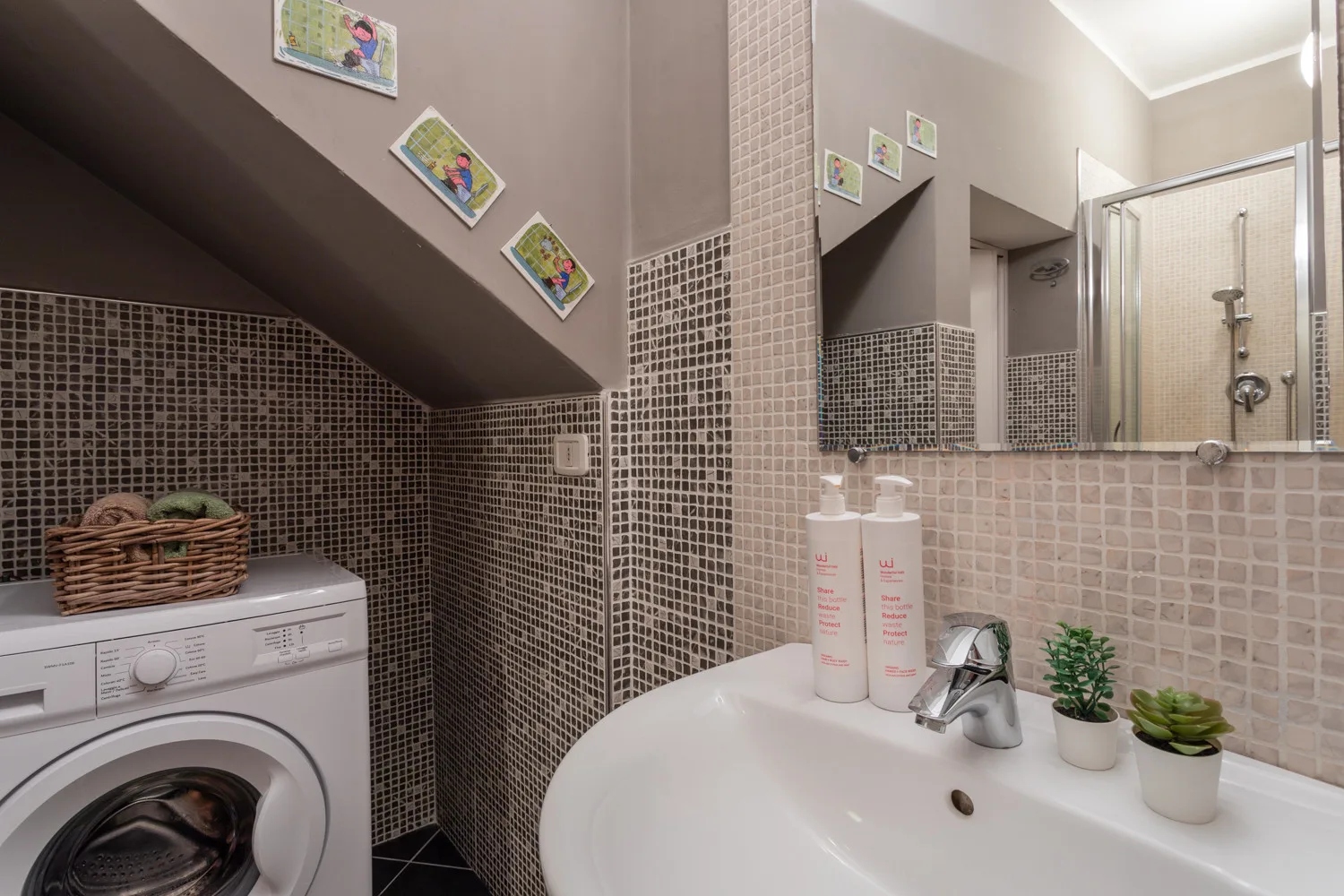 Un baño alicatado con lavabo, espejo, ducha y lavadora.