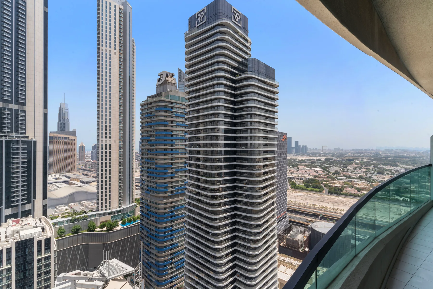 Panorámica urbana desde un balcón de un edificio alto, bajo un cielo despejado.