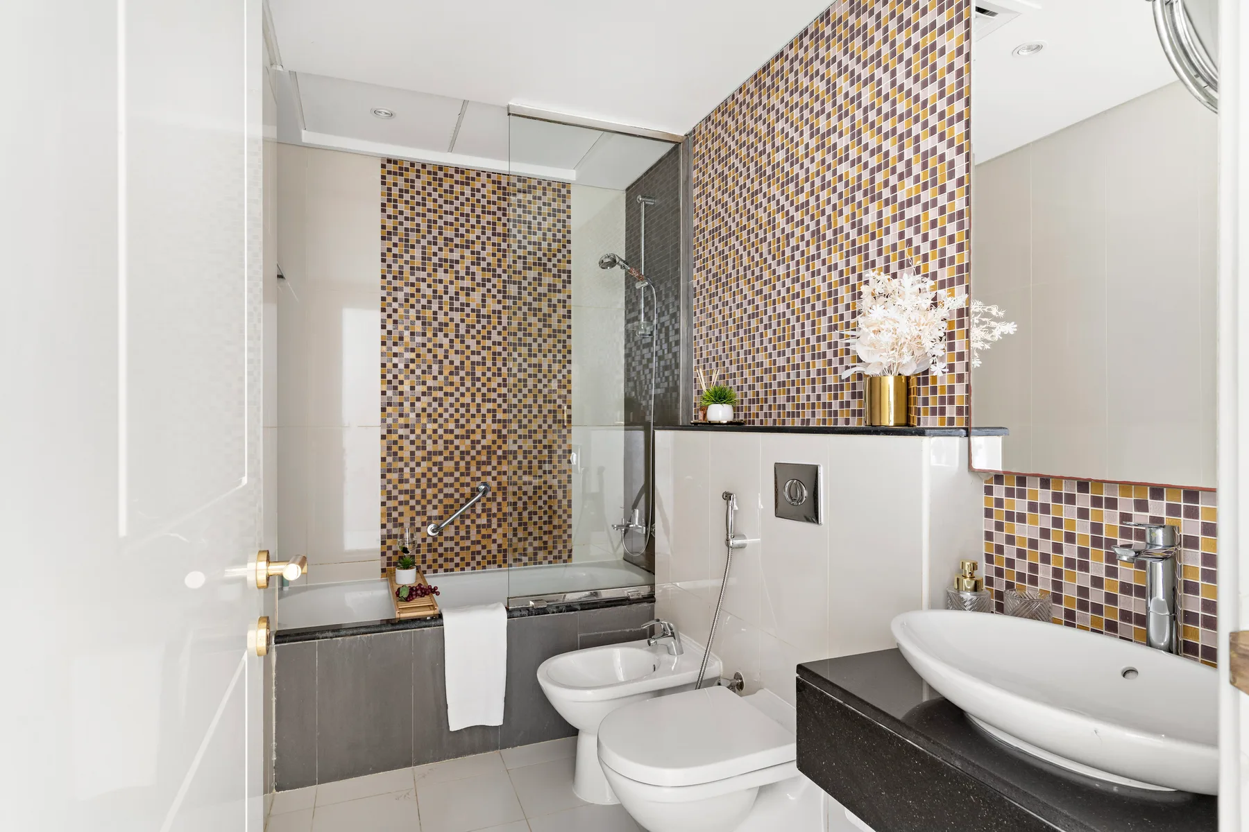 Un baño con bañera, ducha y detalles de mosaico.