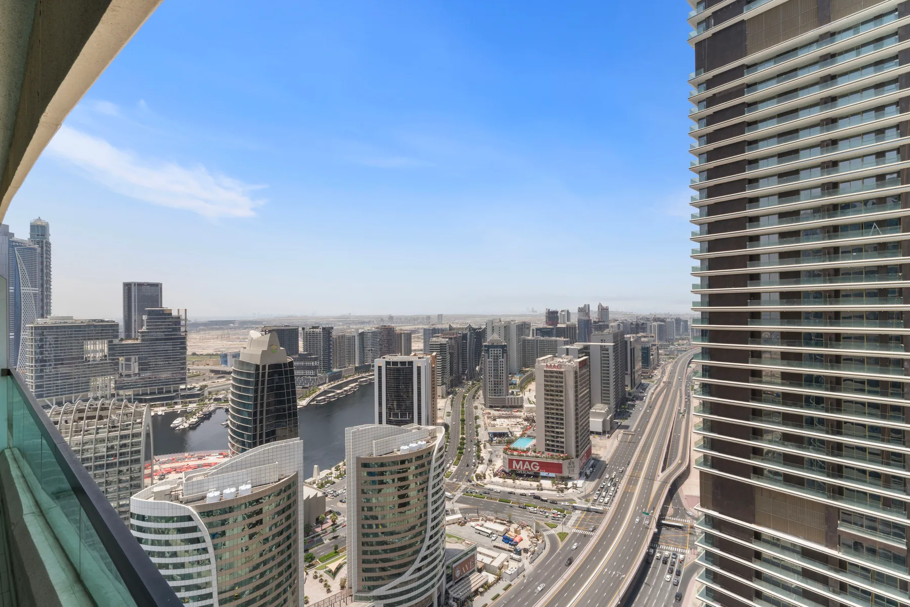 Panorámica urbana desde un balcón, con edificios y carreteras abajo.