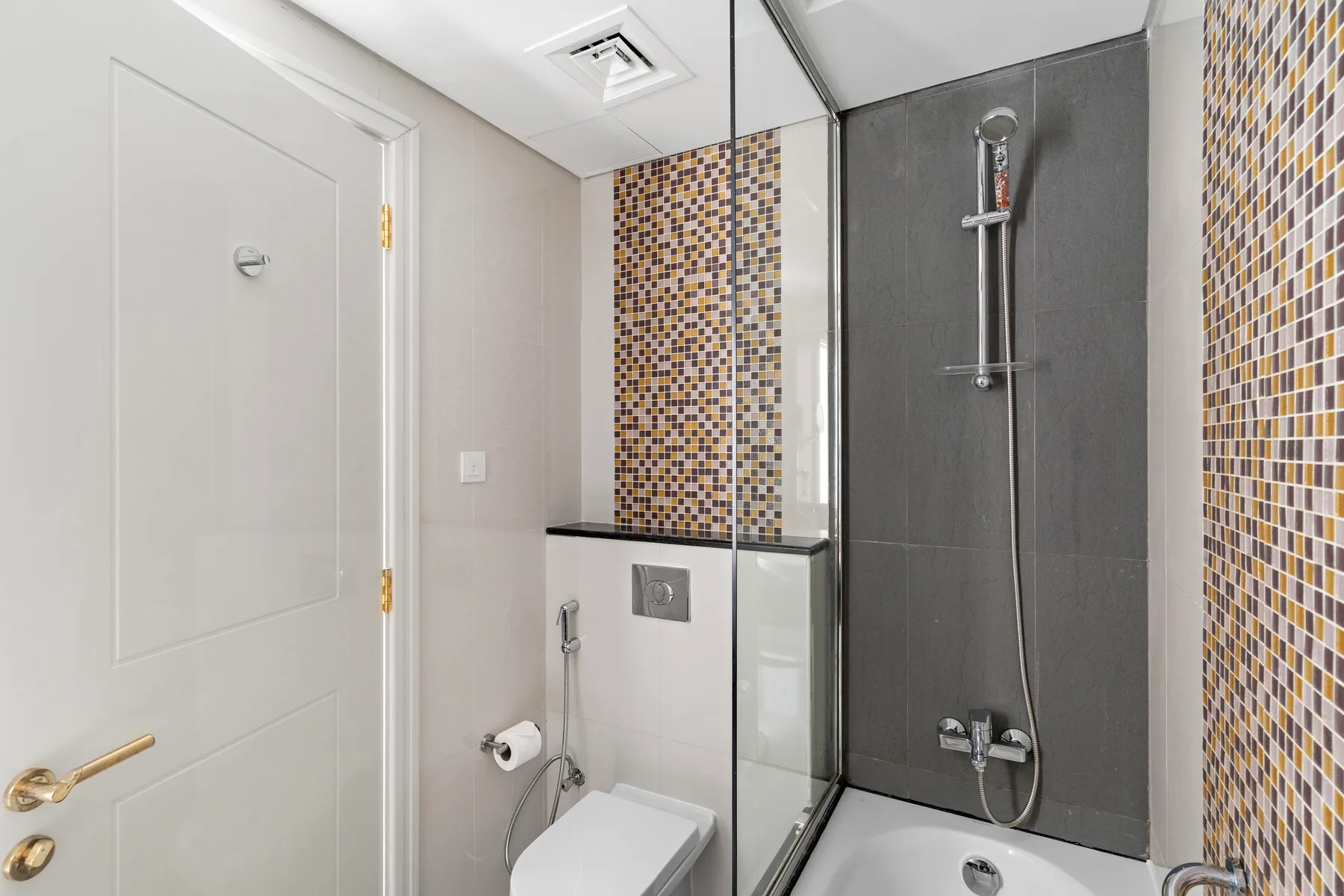 Un baño con bañera, ducha y paredes de azulejos estampados.