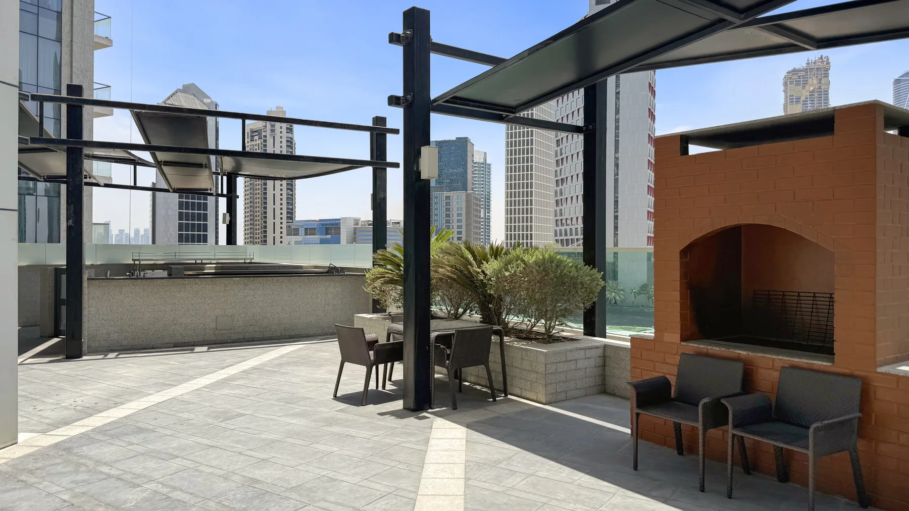 Una terraza en la azotea con asientos al aire libre y una estructura de ladrillo para barbacoa.