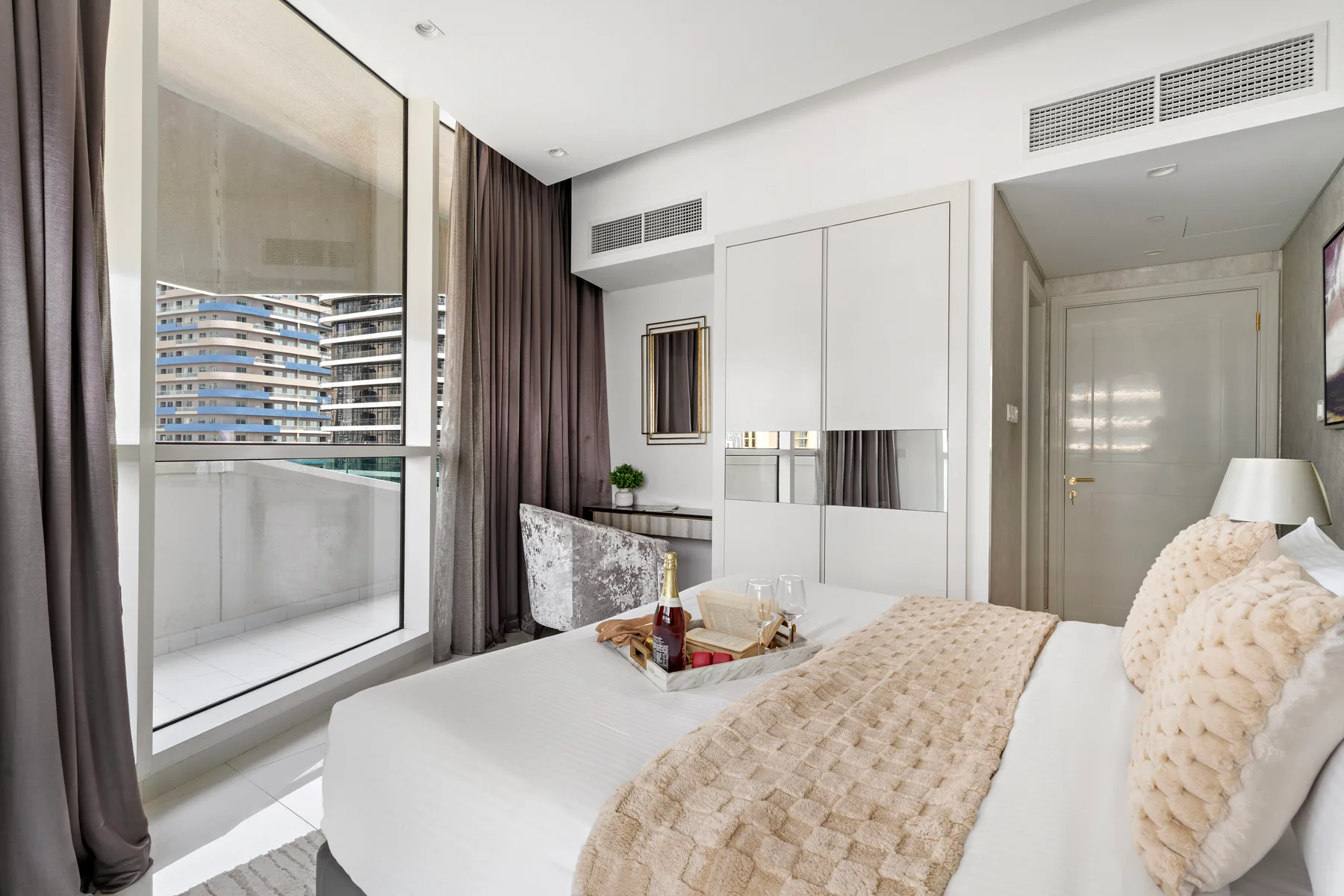 Un dormitorio luminoso con una cama grande junto a ventanales.