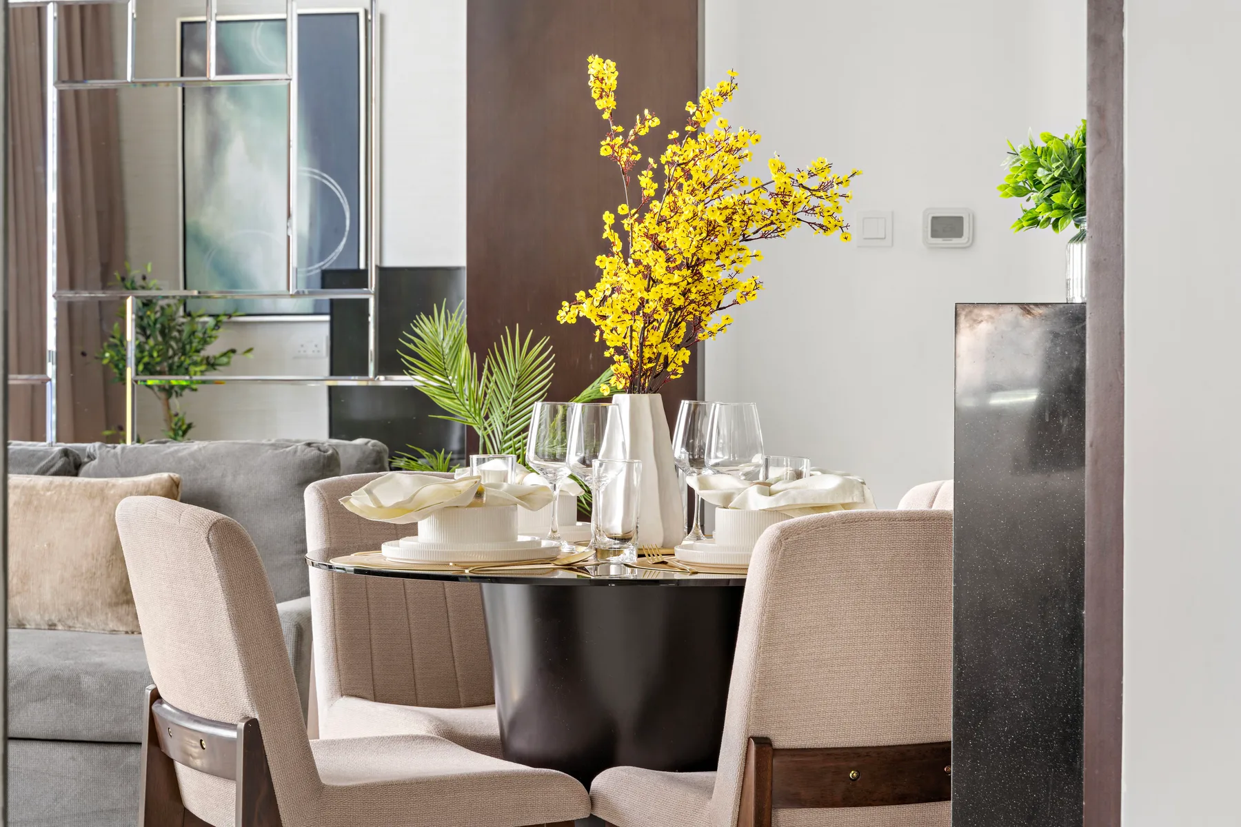 Un comedor con la mesa puesta y un jarrón con flores amarillas.