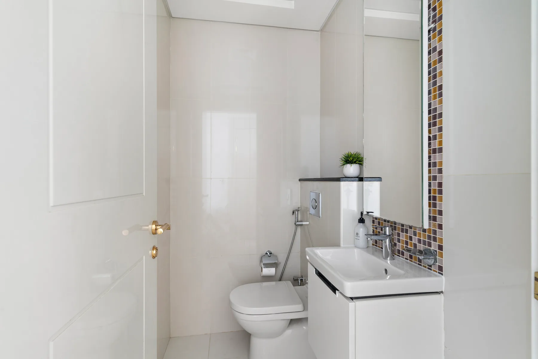 Un baño luminoso con inodoro, lavabo y un gran espejo de pared.