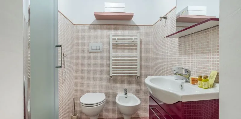 A tiled bathroom with a shower, toilet, bidet, and sink.