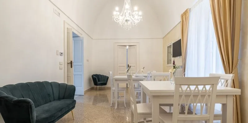 Un comedor luminoso con una mesa larga y sillas junto a ventanas con cortinas.
