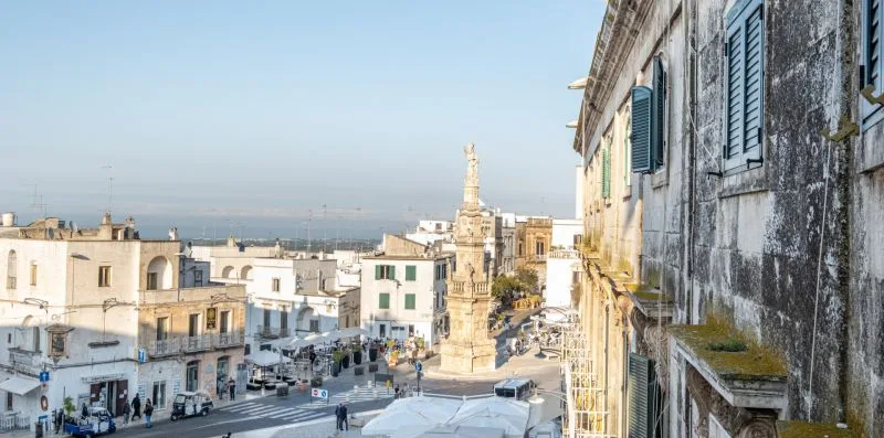 Una plaza histórica está rodeada de edificios de piedra y un monumento central.
