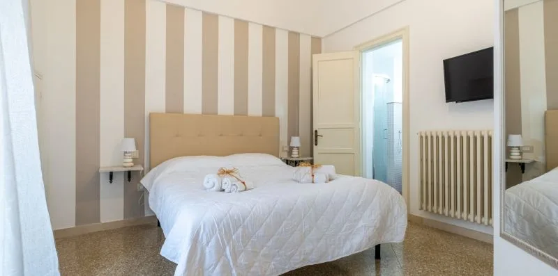 A bedroom with a bed against a wall of vertical striped wallpaper.