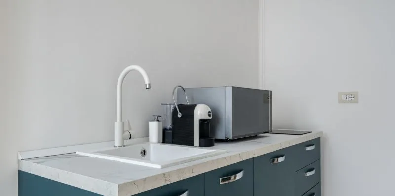 Una encimera de cocina con una cafetera y un fregadero.
