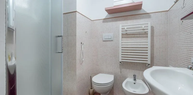 A tiled bathroom with a toilet, bidet, and sink.