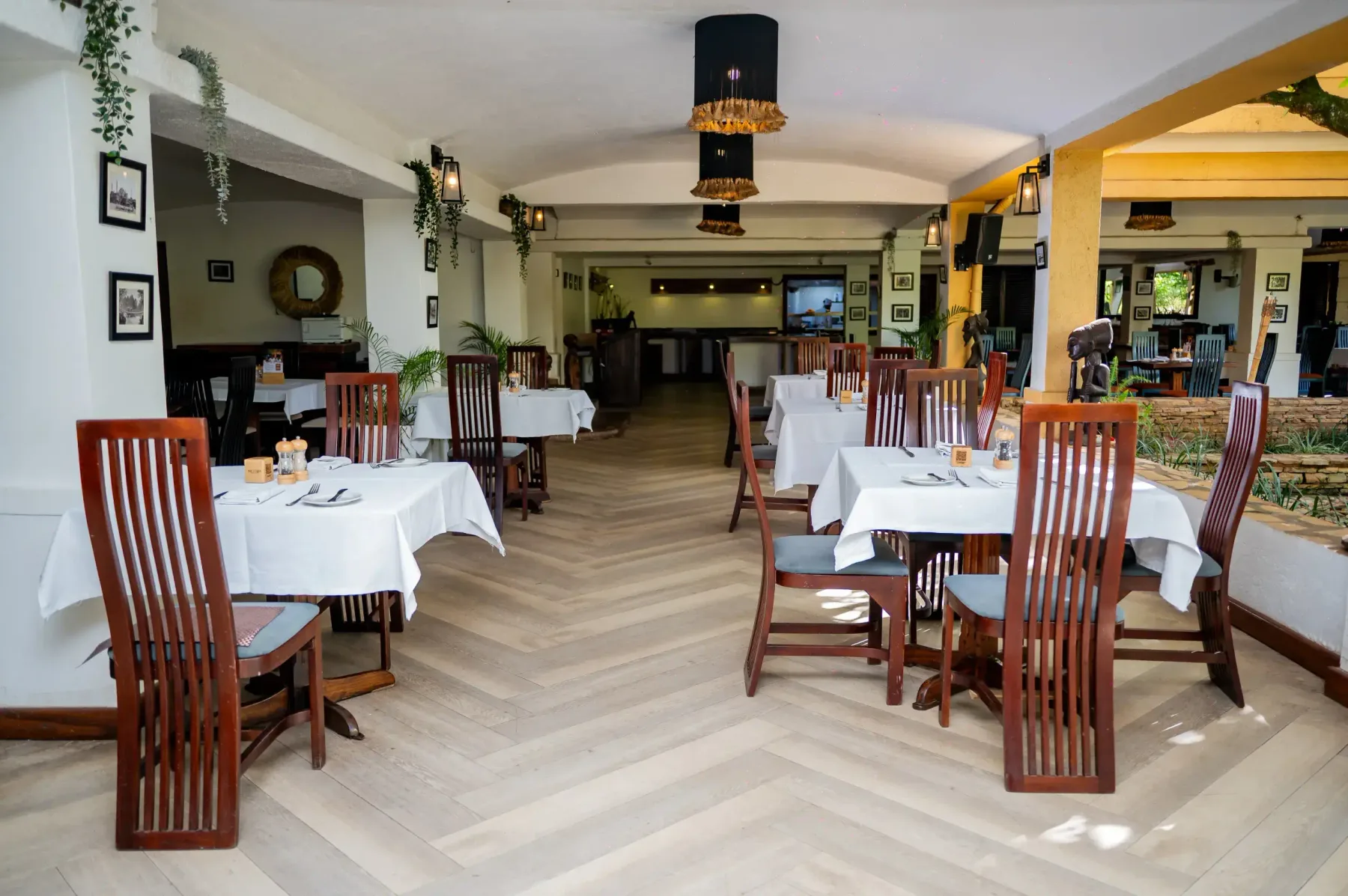 Comedor Equatoria preparado bajo lámparas colgantes de ratán