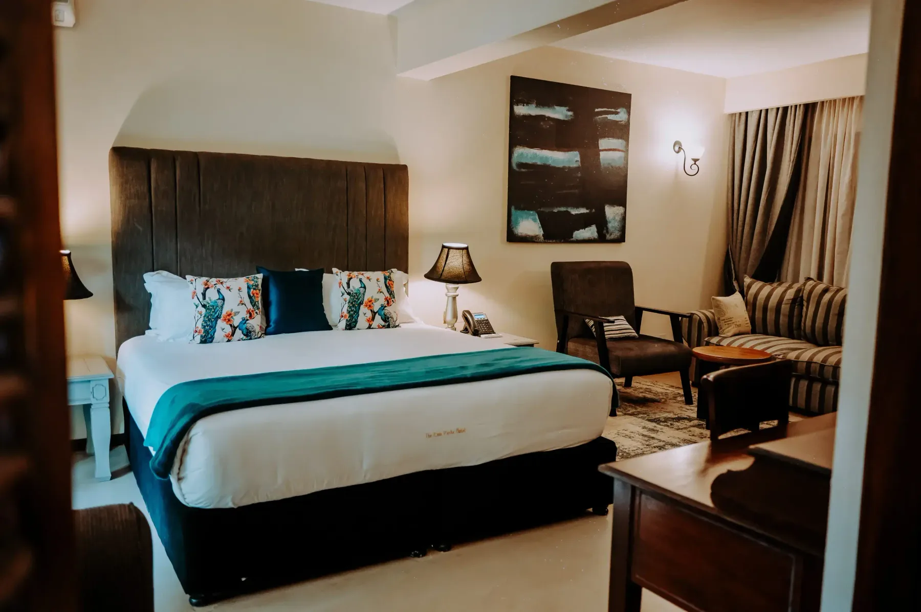 Deluxe Room with a king bed, teal runner and armchair
