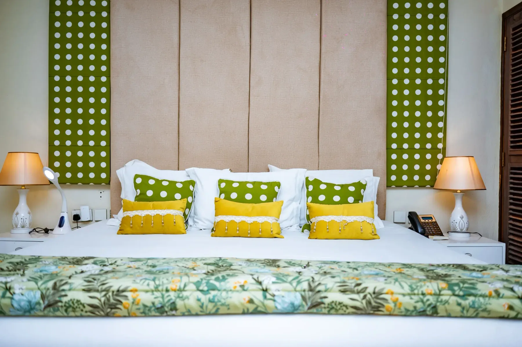 Cama de la Suite VIP contra una pared con cabecero tapizado en verde