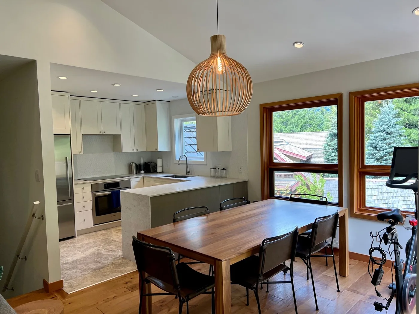 Comedor con una mesa de madera junto a una cocina luminosa.
