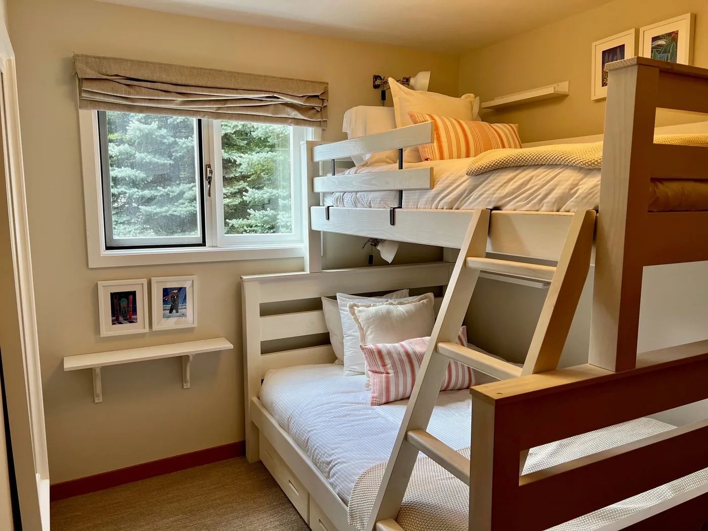 Un dormitorio compacto con dos camas apiladas y una ventana con vista a los árboles.