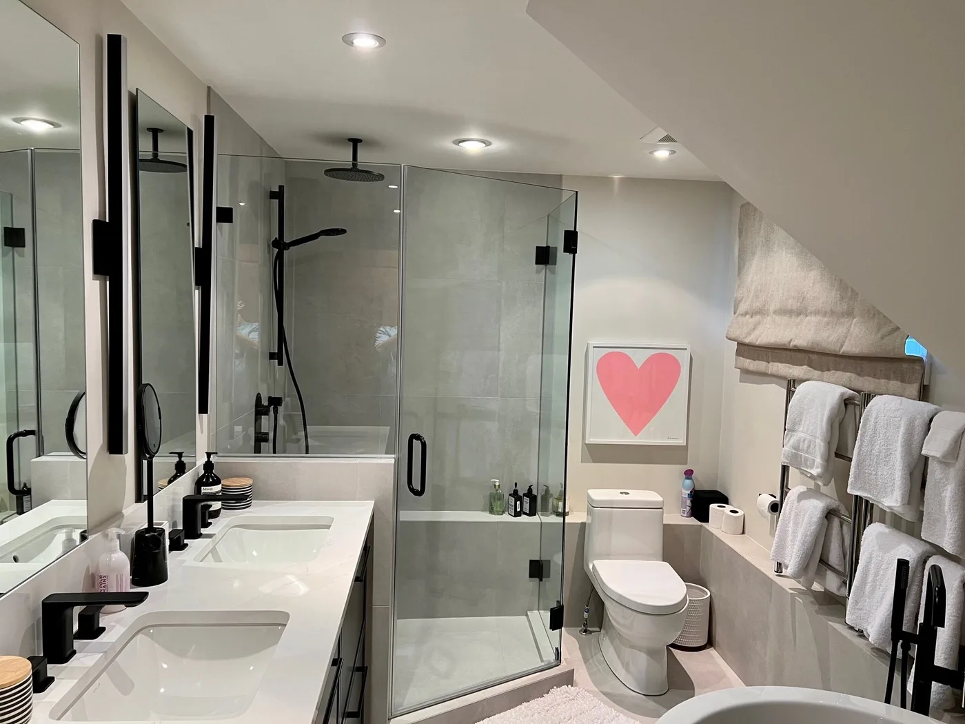 Un baño con ducha de vidrio, lavabo e inodoro.