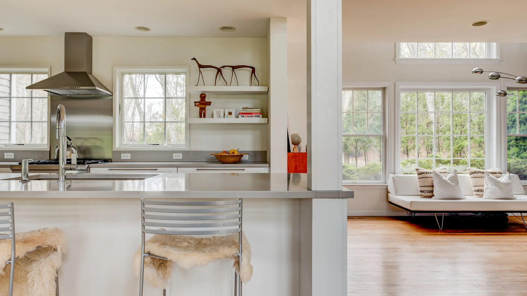 Cocina y sala de estar de concepto abierto con grandes ventanas y un sofá.