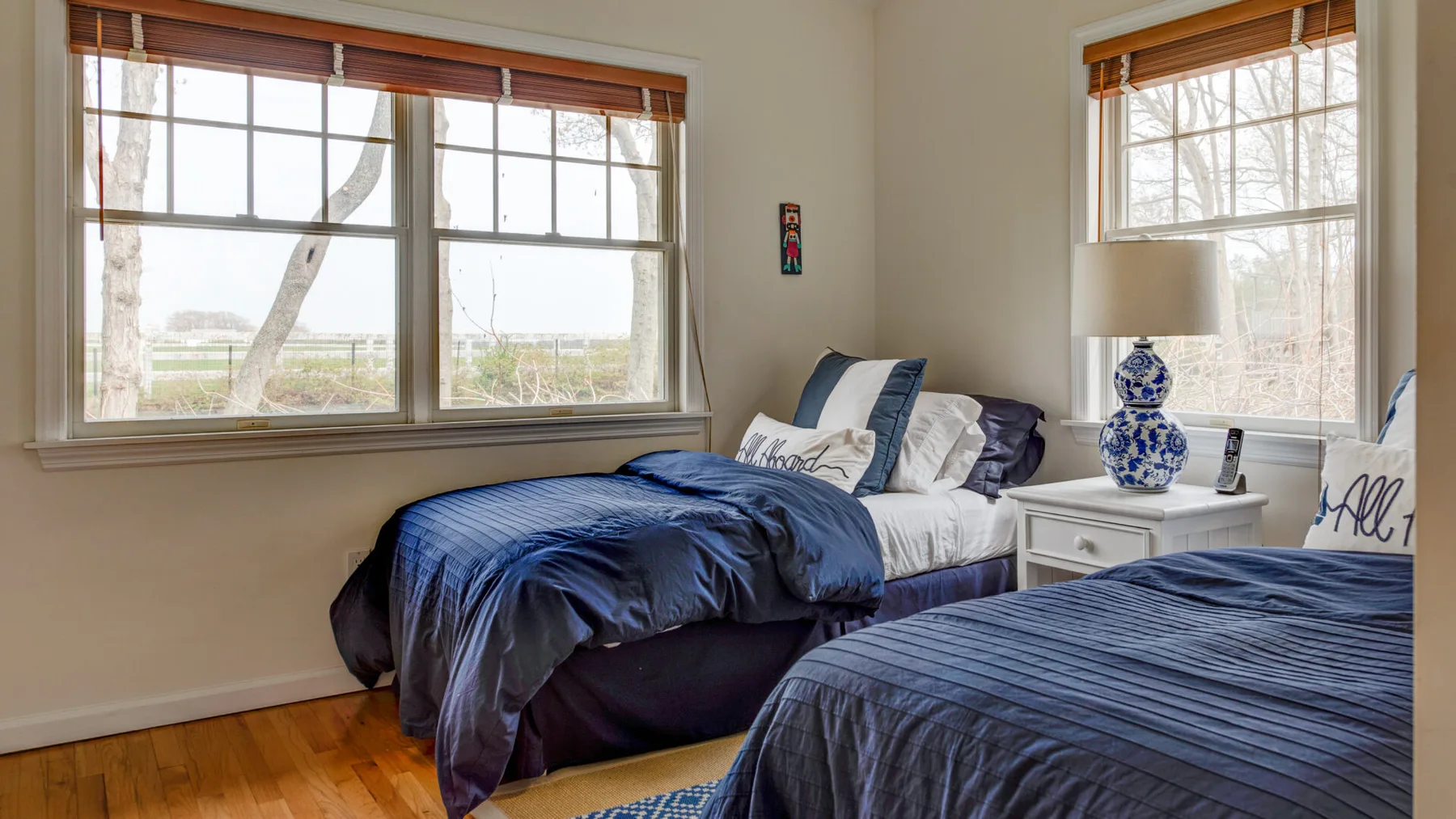 Un dormitorio con dos camas, ropa de cama blanca y grandes ventanas.