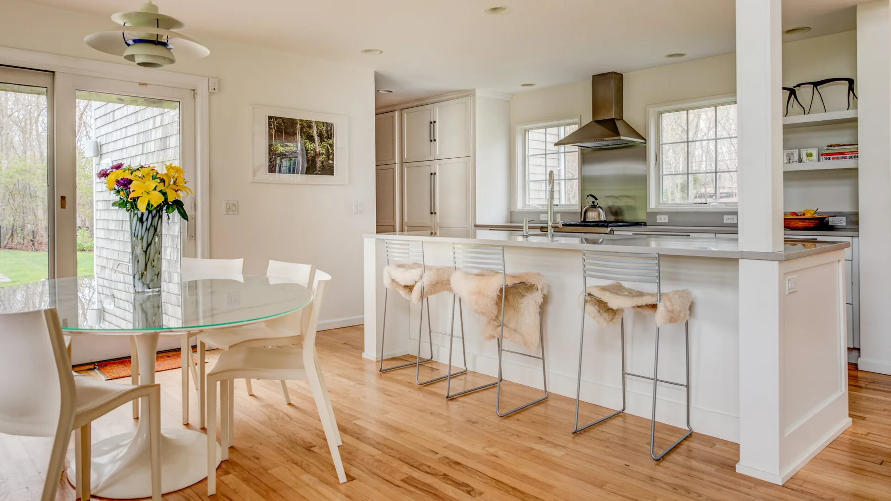 Una luminosa cocina-comedor cuenta con una barra con asientos y una mesa de comedor de vidrio.
