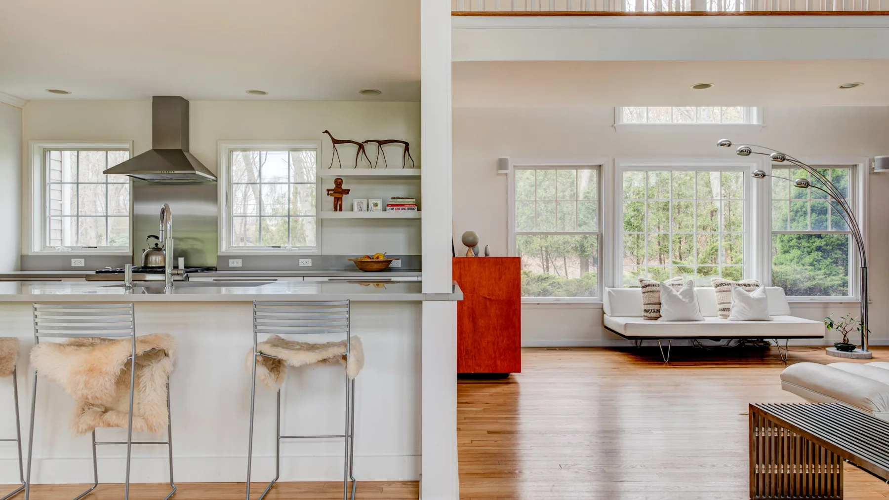 Una cocina abierta al salón, con asientos de barra y ventanas grandes.
