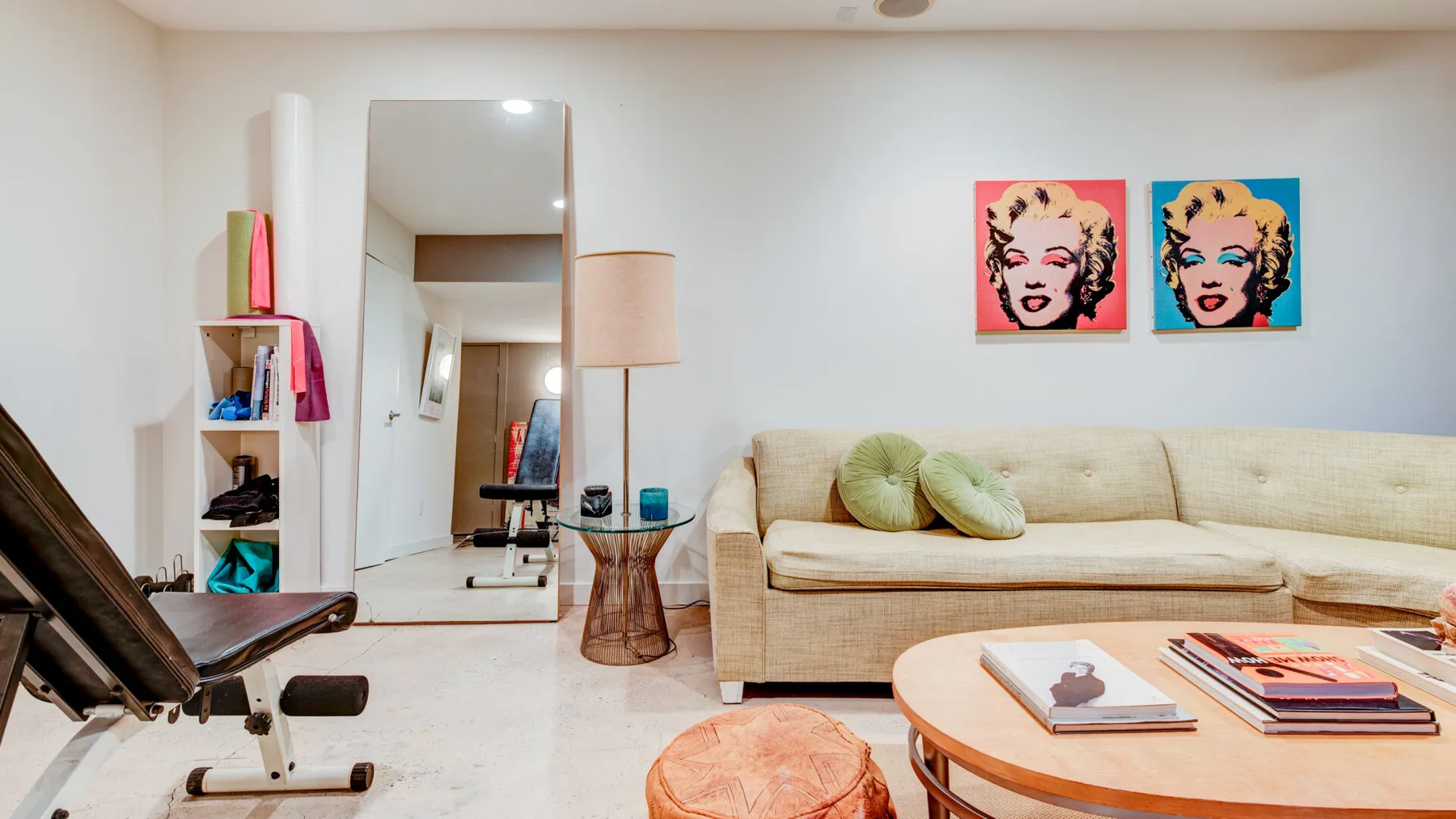 Una sala de estar con un sofá beige y arte pop colorido en la pared.