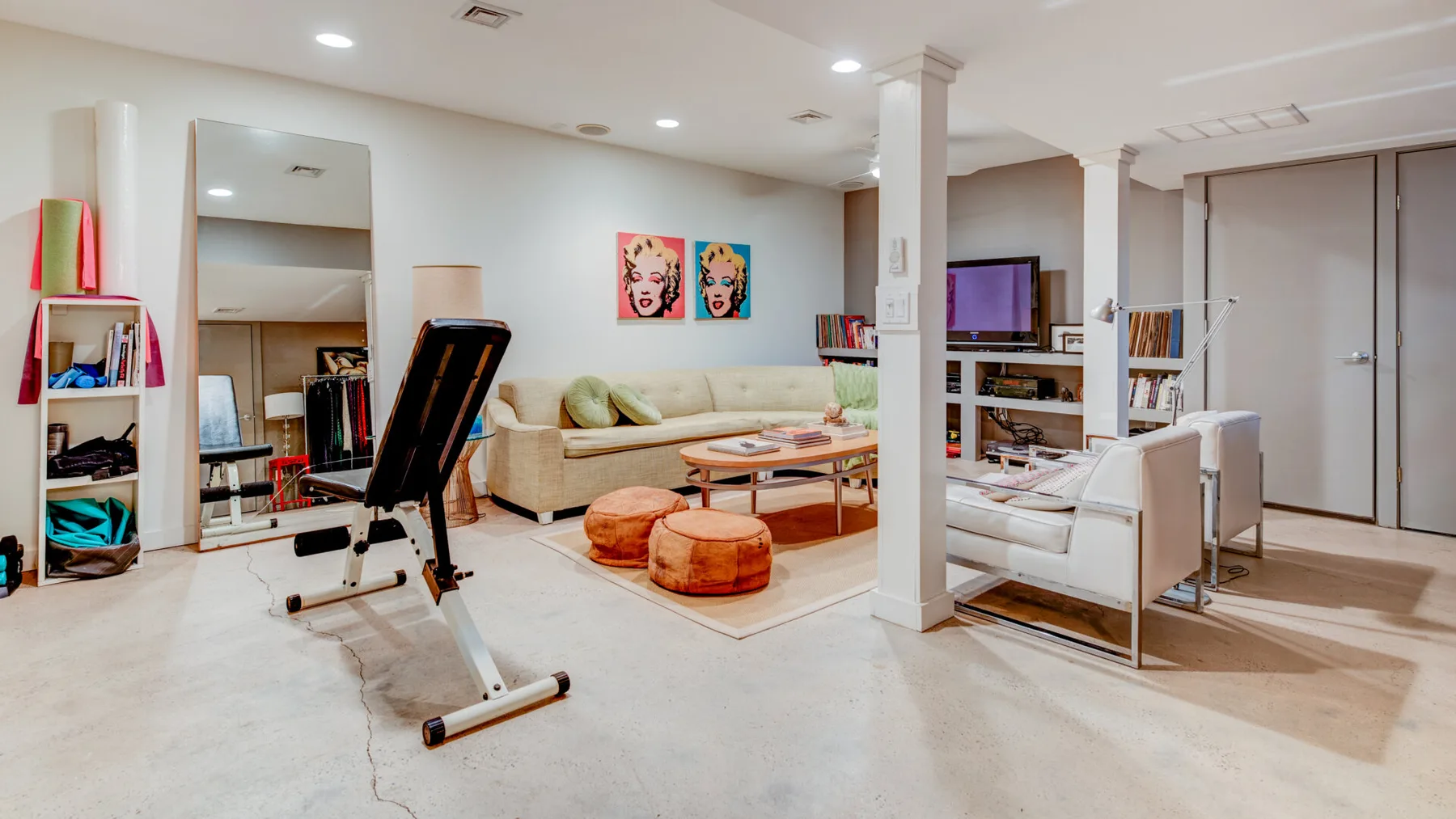 Una sala de estar con sofá seccional, mesa de centro y equipo de ejercicio.