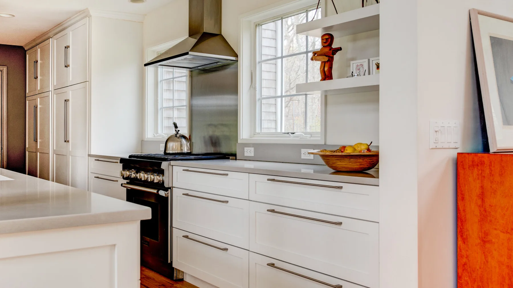 Una cocina luminosa con gabinetes blancos, una estufa y una encimera.