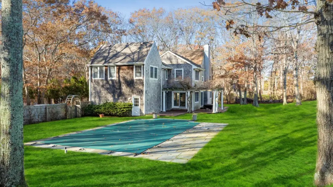 Una casa grande da a una piscina cubierta y un césped verde.