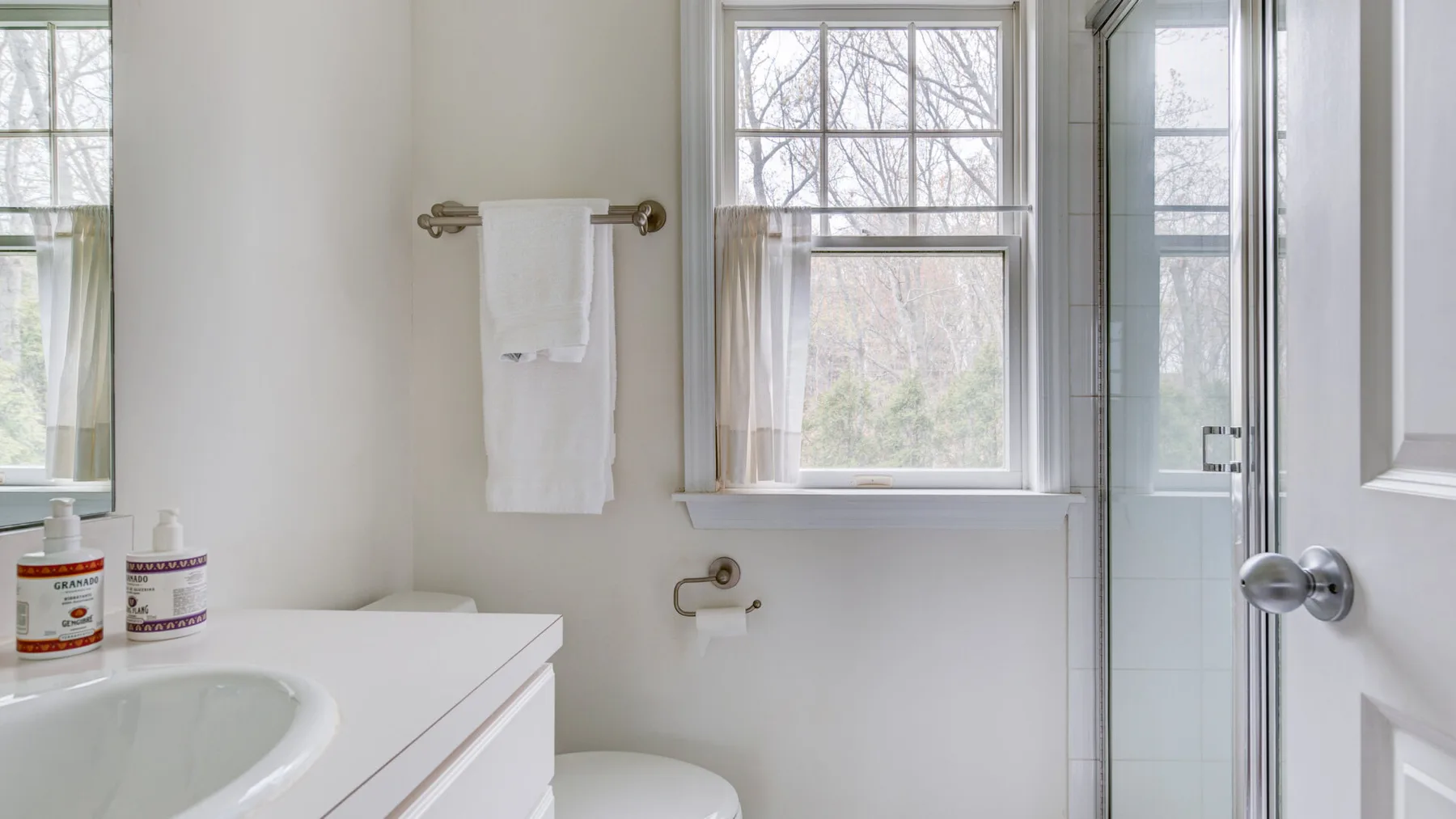 Un baño luminoso con lavabo, inodoro y ducha de vidrio.