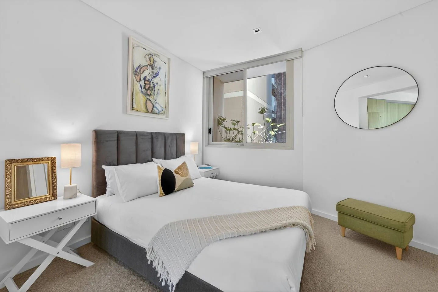 El dormitorio con cama queen ofrece un refugio sereno con alfombras suaves, ropa de cama mullida, una decoración en tonos neutros y una tenue luz natural.